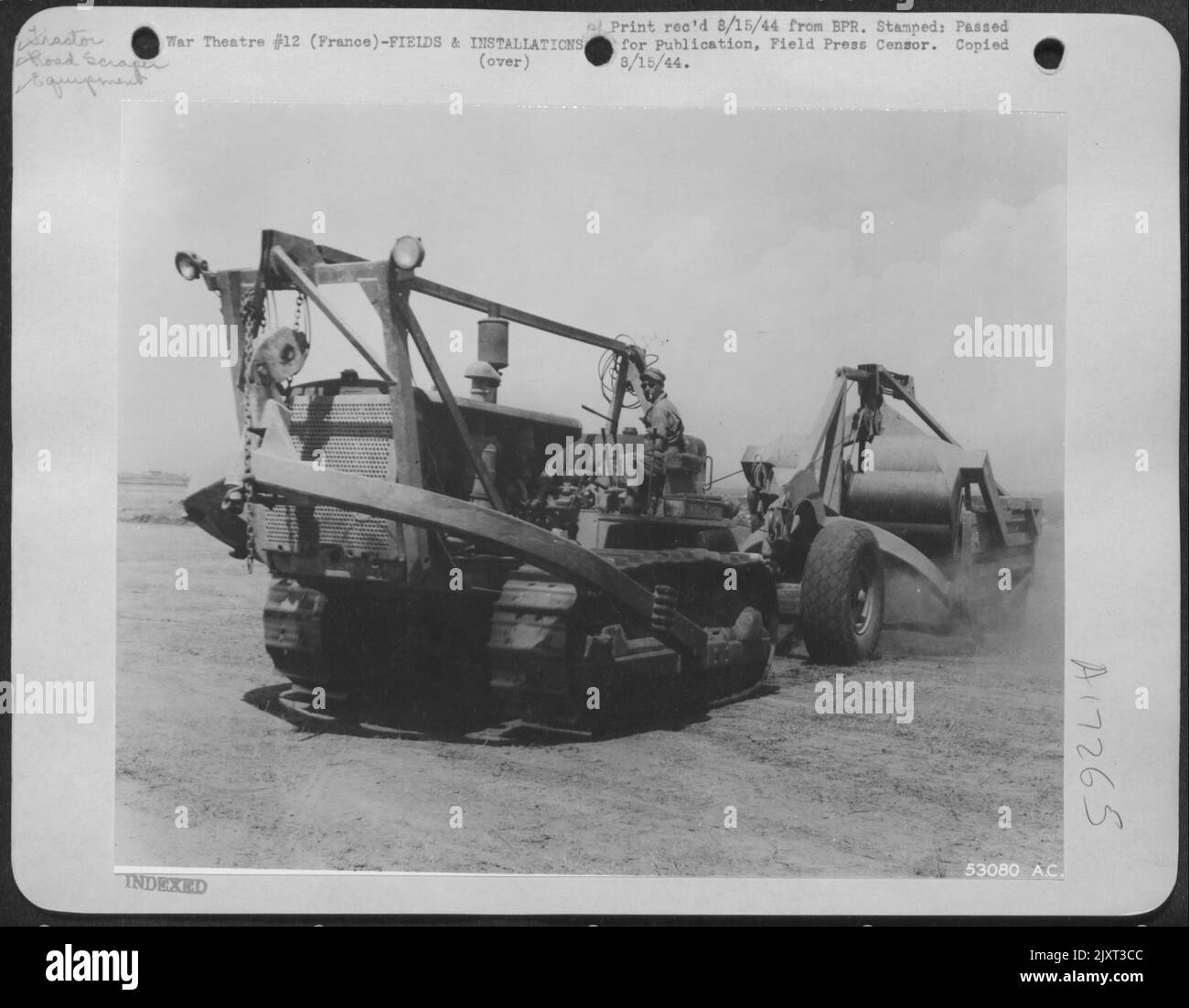 Die Bewässerungsgräben, die die Breite der Landebahn durchflossen, wurden bereits teilweise von Bulldozern ausgefüllt. Der von einem schweren Traktor geschleppte Straßenschaber bewegt die Erde von einem nahegelegenen Ort und legt sie gleichmäßig entlang des Grabens, um die Füllung zu vervollständigen. Die Straße Stockfoto