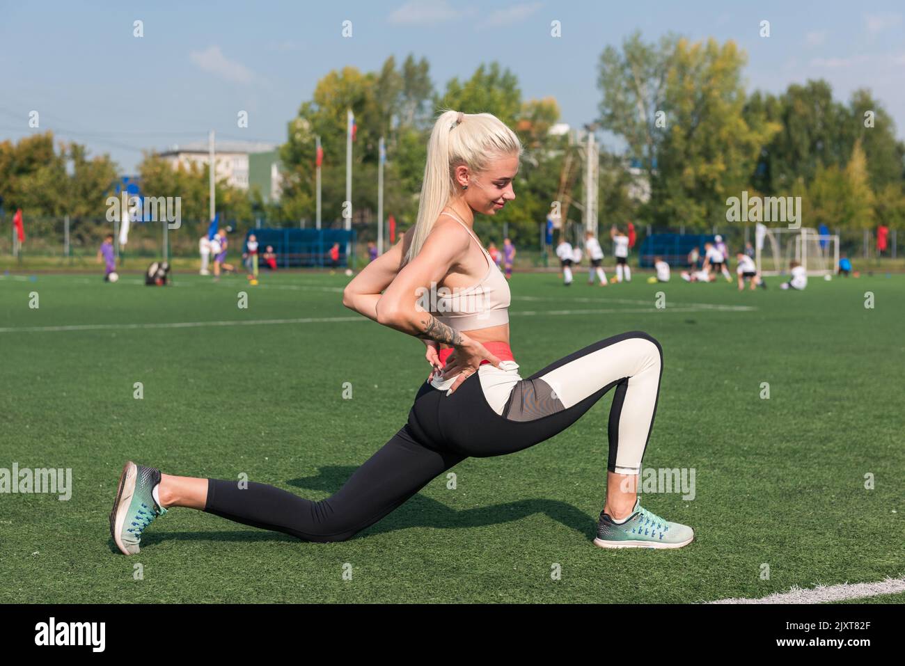 Junge sportliche Frau in Sportbekleidung, die sich im Stadion ausdehnt Stockfoto