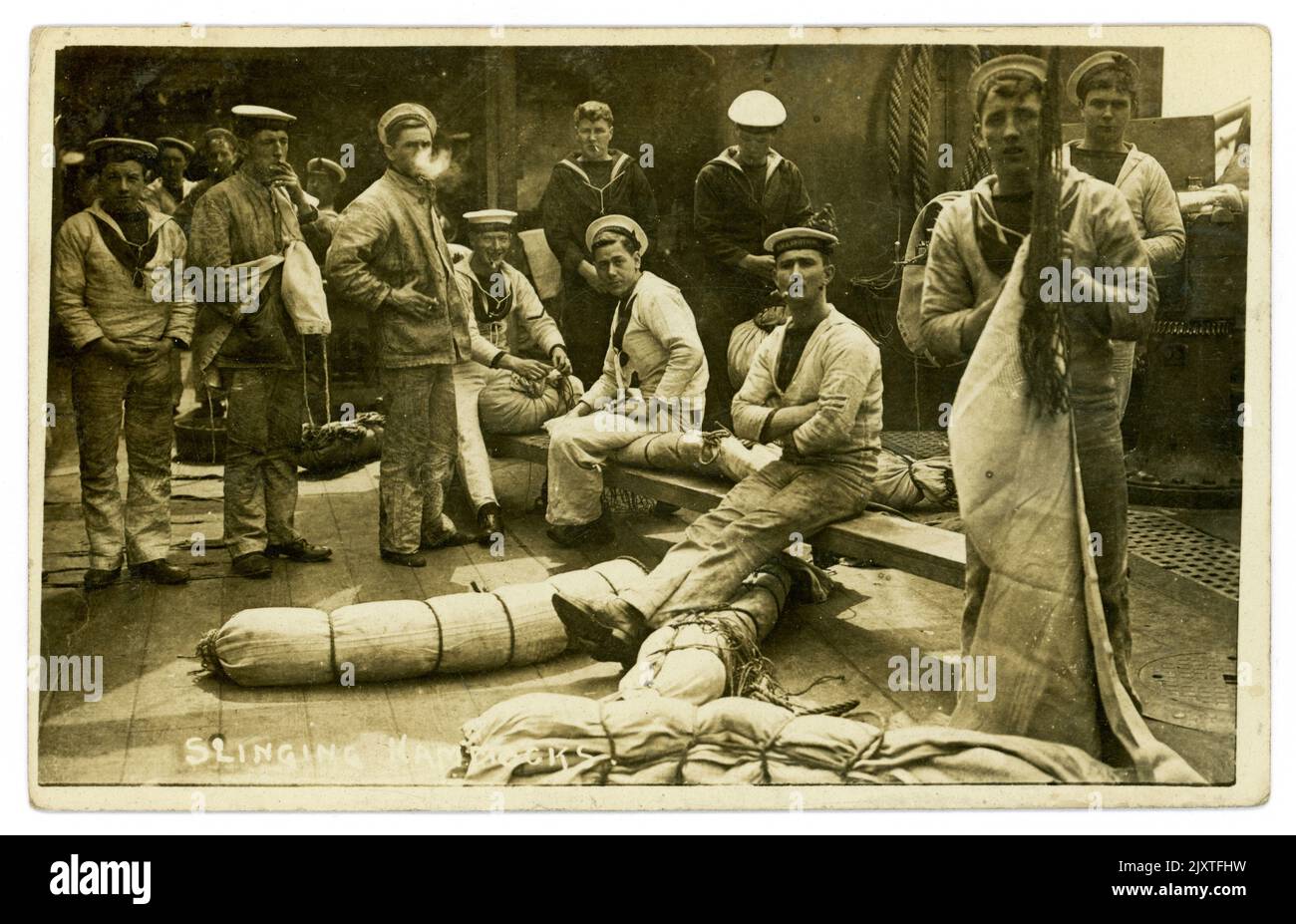 Originalpostkarte aus der Zeit WW1, auf der eine Gruppe von Matrosen der Royal Navy Hängematten auf einem Schiff schleudern, viele Charaktere, ein Mann raucht, datiert und am 5. 1916. Oktober, kurz vor Kriegsende, aus Portsmouth, Großbritannien, gepostet wird Stockfoto