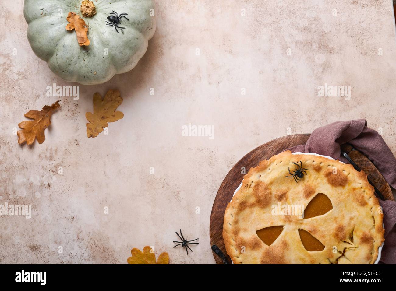 Halloween-Essen. Hausgemachter Kürbiskuchen oder Torte mit einem gruseligen Gesicht für Halloween auf einem Holztisch. Speicherplatz kopieren. Halloween-Food-Konzept. Stockfoto