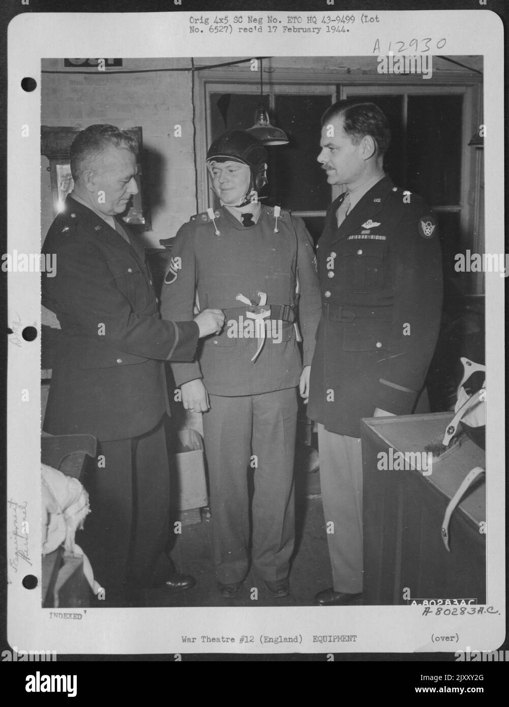 Brig. General Malcolm C. Grow (links) und Brig. General Leon Johnson schaut über die modifizierte Weste und den von S/Sgt getragenen New Manganese Steel-lined Helm. Ambrose T. Hansen. London, England, 14. Dezember 1943. Stockfoto