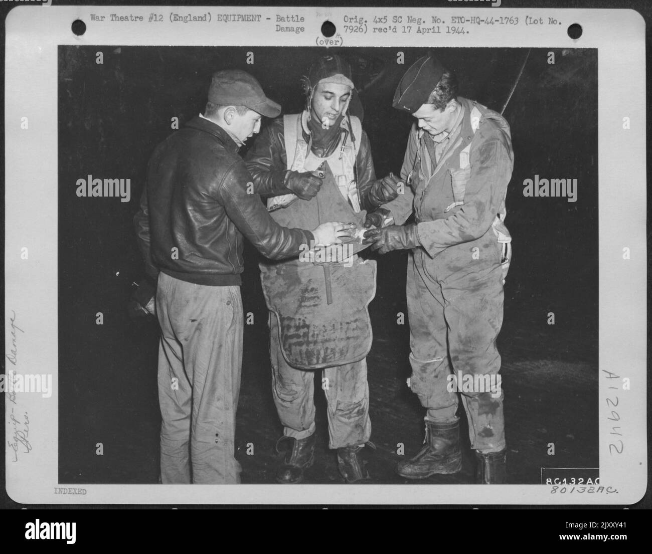 Auf einem Flugplatz in Beford, England, LT. L.P. Bowers, Grand Rapids, mich., Centre, Shows S/Sgt. D.E. Wonderly, Sherwood, Ohio, links und LT. J.E. McLain, Pueblo, Colorado, wo sein Flak-Anzug während Eines Missi ein Stück Schrapnel daran hinderte, sein Bein zu durchstechen Stockfoto