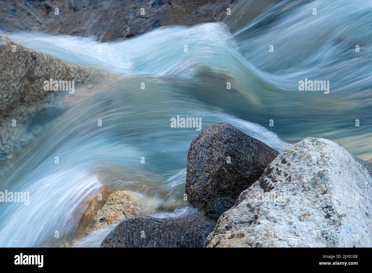 Langzeitbelichtung des fließenden Wassers eines Baches in den Schweizer Alpen Stockfoto