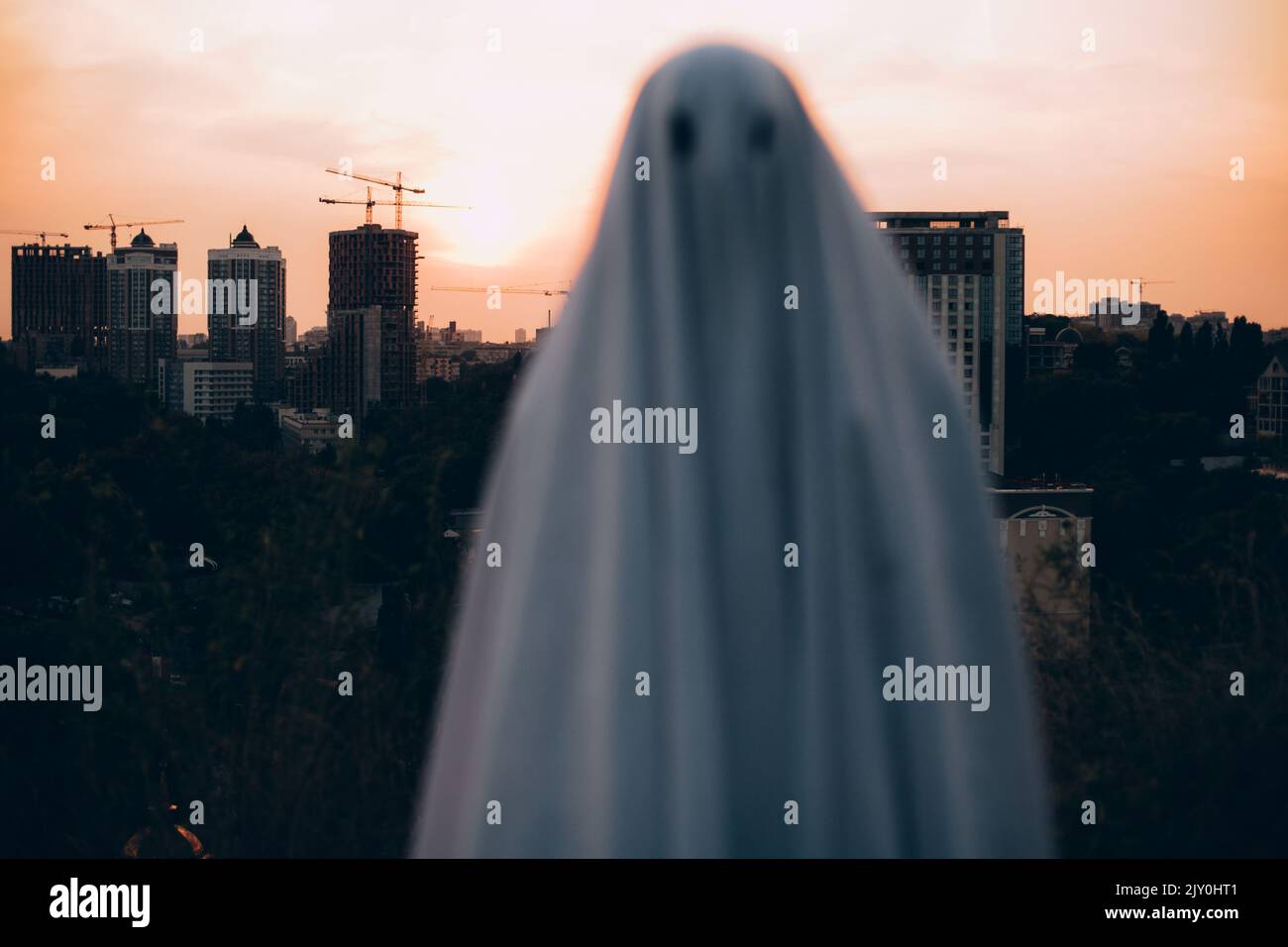 Gruseliger Geist, der an Halloween gegen die Abendstadt steht Stockfoto