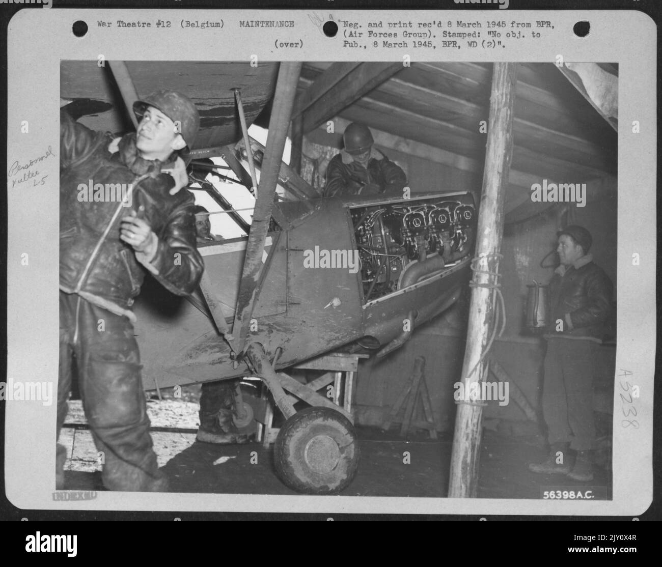 Dies ist der einzige Hangar für die Flugzeuge des Liaison Squadron. Nur ein Windschutz für die Mechaniker, er besteht aus Schrottholz und einem deutschen Zeltboden. Von links nach rechts: CPL. Henry Brief, 351 Riverdale Ave., Brooklyn, N.Y.; Sgt. Kirby L. Jensen, Albany Stockfoto