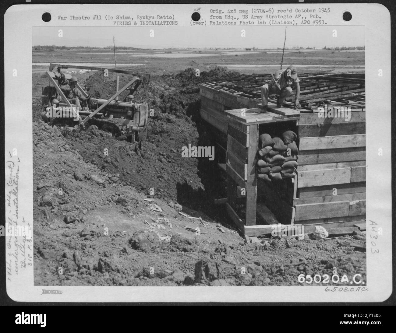 Bulldozer, der die Erde bewegt, um die unterirdische Kommandopostelle zu bedecken, um sie von der Operations-Abteilung und anderen Mitarbeitern der 318Th Fighter Group während japanesischer Luftangriffe auf IE Shima, Ryukyu Retto zu verwenden. Stockfoto