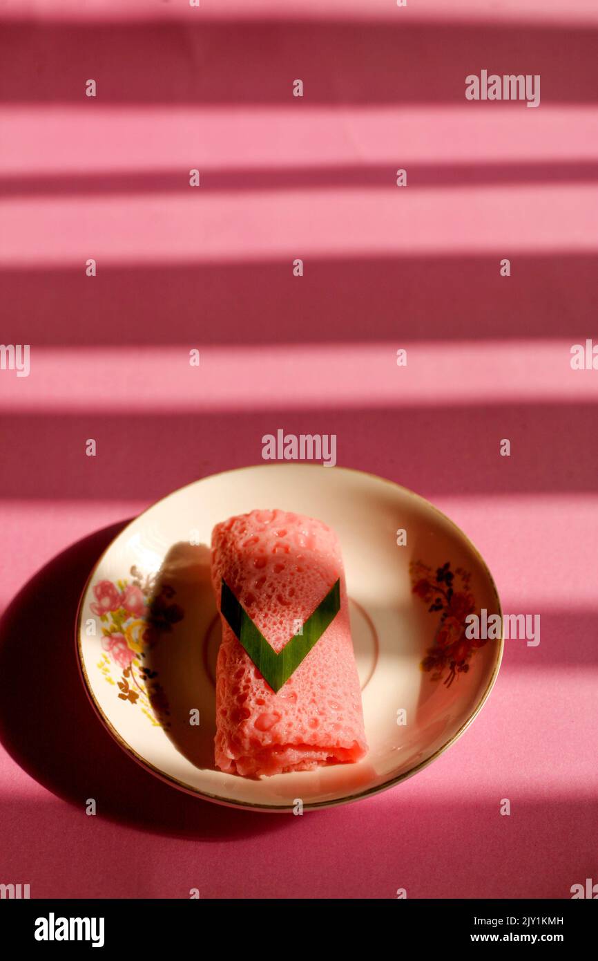 Rosafarbene Pfannkuchenrollen auf dem Teller. Traditionelles indonesisches oder malaysisches Essen namens dadar Gulung. Stockfoto