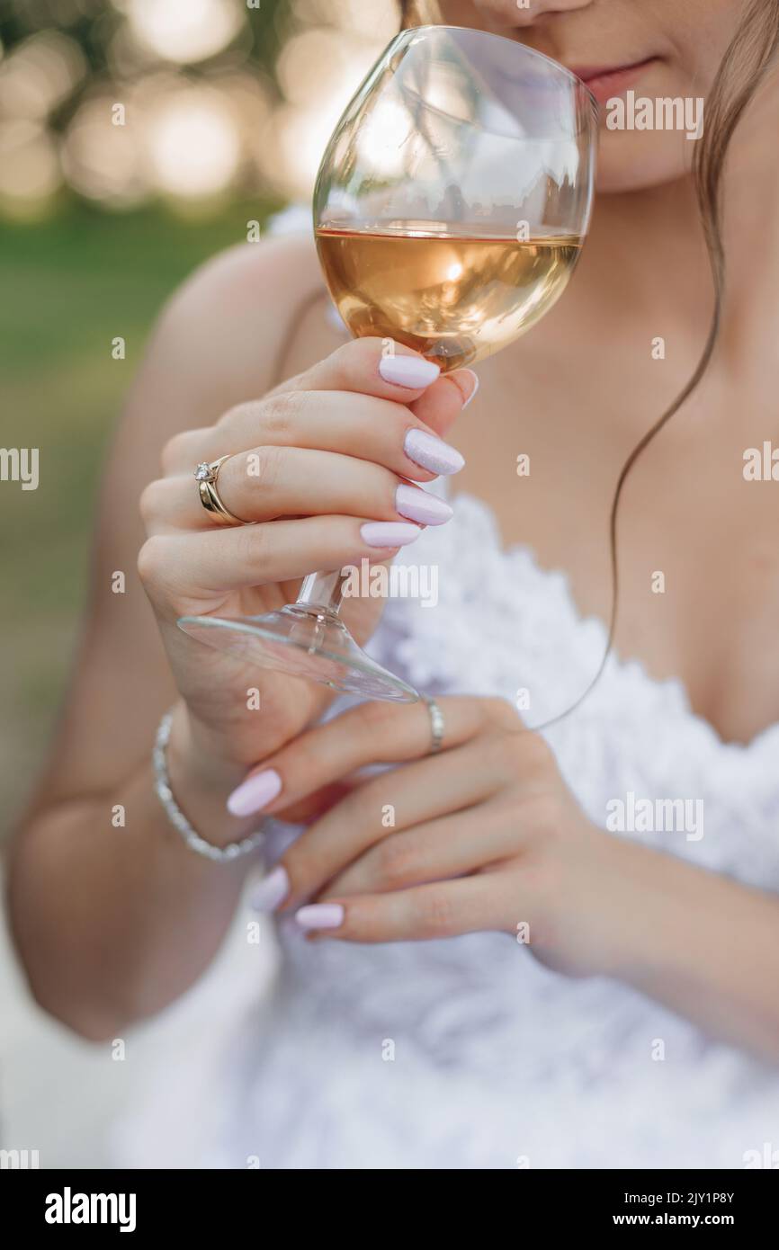 Vertikales Porträt einer ausgeschnittenen Braut im Hochzeitskleid und Schleier, die alkoholfreien Sekt trinkt und verkostet Stockfoto