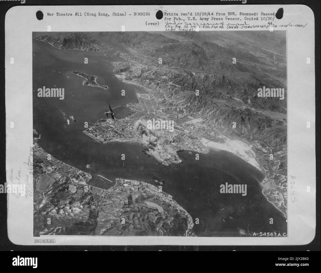 Die Japaner dachten, die Ostchinesischen Stützpunkte von 14. seien zerstört; sie verlegten die Schifffahrt nach Hongkong, um der Geißel der Nimitz-Task Force zu entkommen. 14. Kämpfer und Bomber haben sie dort gefangen. Rauchwolken von den Kowloon Docks und den Bahnhöfen. Japanischer Kämpfer (links in der Mitte) Stockfoto