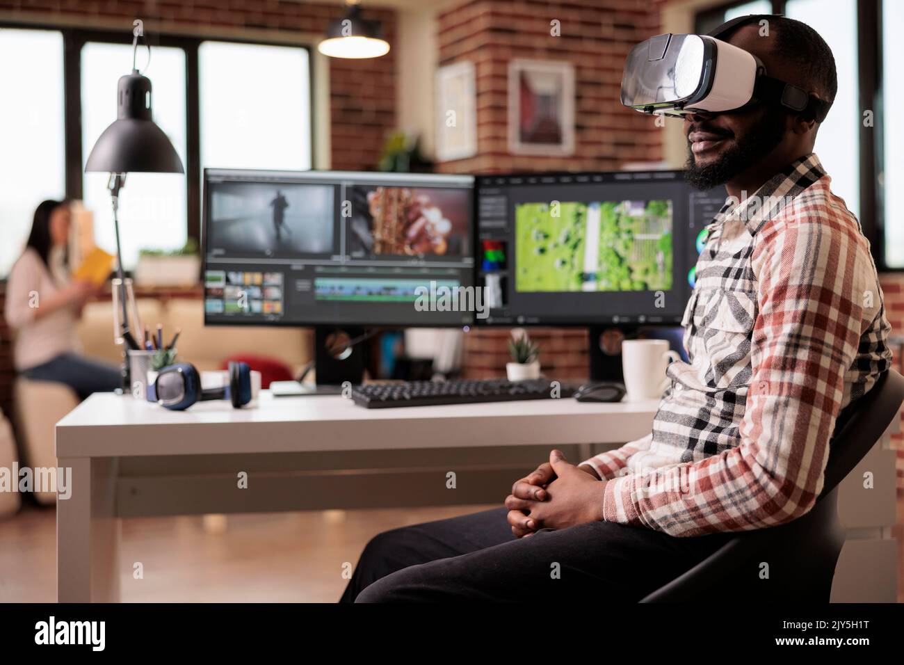 Grafiker, der Videos mit einer VR-Brille bearbeitet, an der Postproduktion mit Virtual-Reality-Headset und kreativer Software am Computer arbeitet. Inhaltsersteller, der Film oder Film macht. Stockfoto