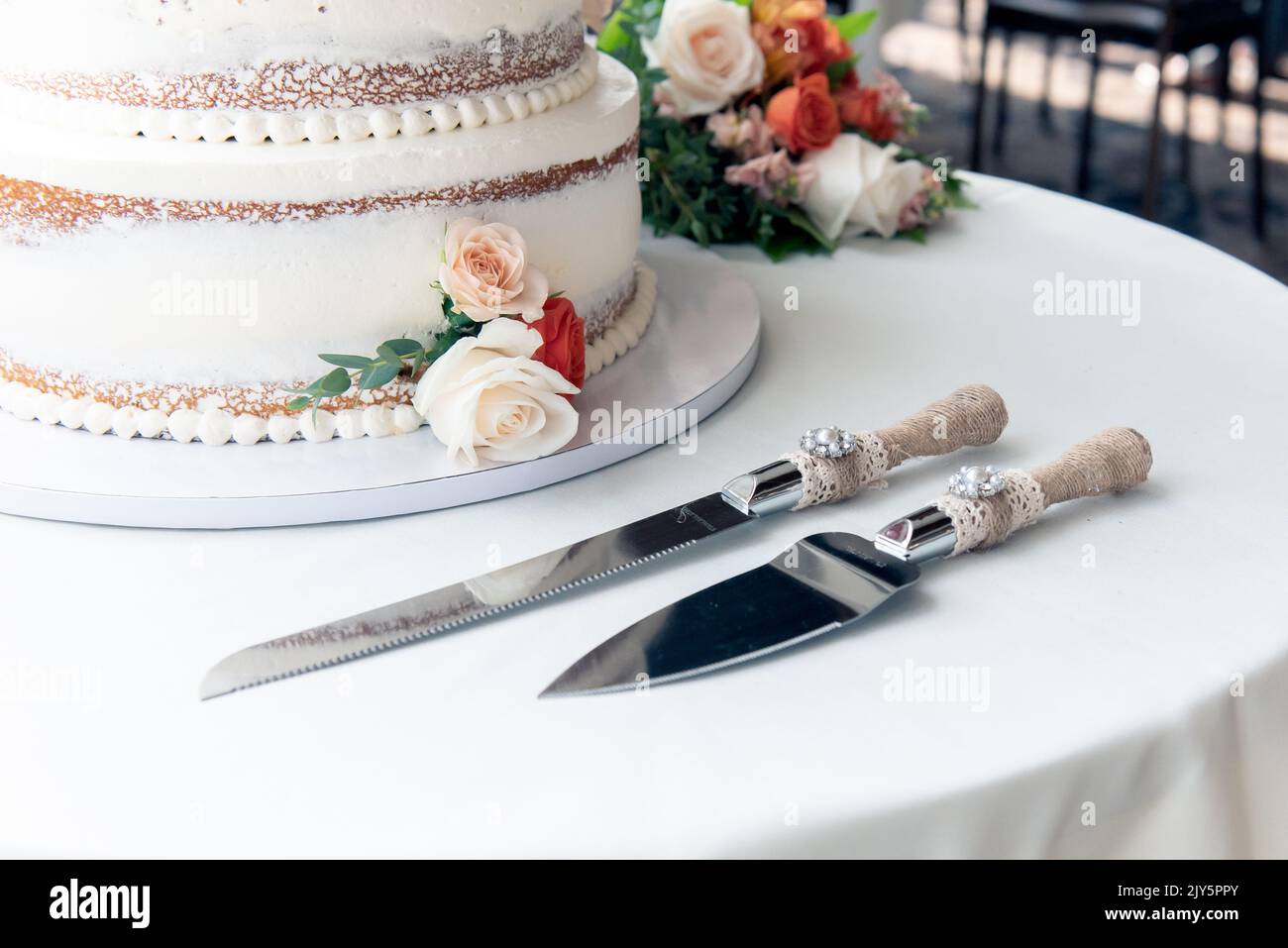 Hochzeitstorte ist neben Edelstahl Utensil Servierset für Braut und Bräutigam, um ein Stück Kuchen schneiden gesetzt. Stockfoto