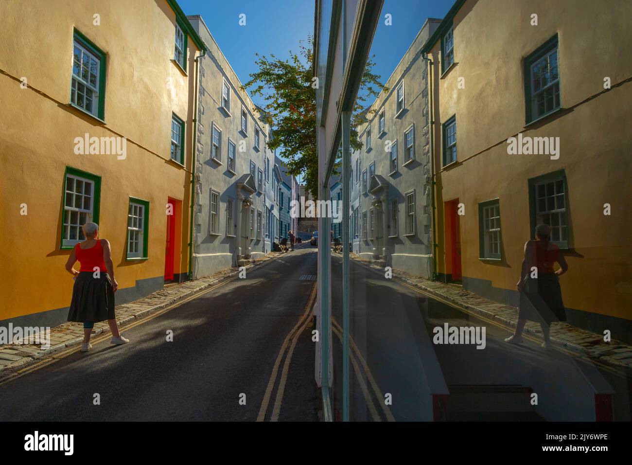 Morgen Straßenszene in der Küstenstadt Lyme Regis, Dorset. Farbenfrohe Gebäude spiegeln sich im Schaufenster wider. Stockfoto