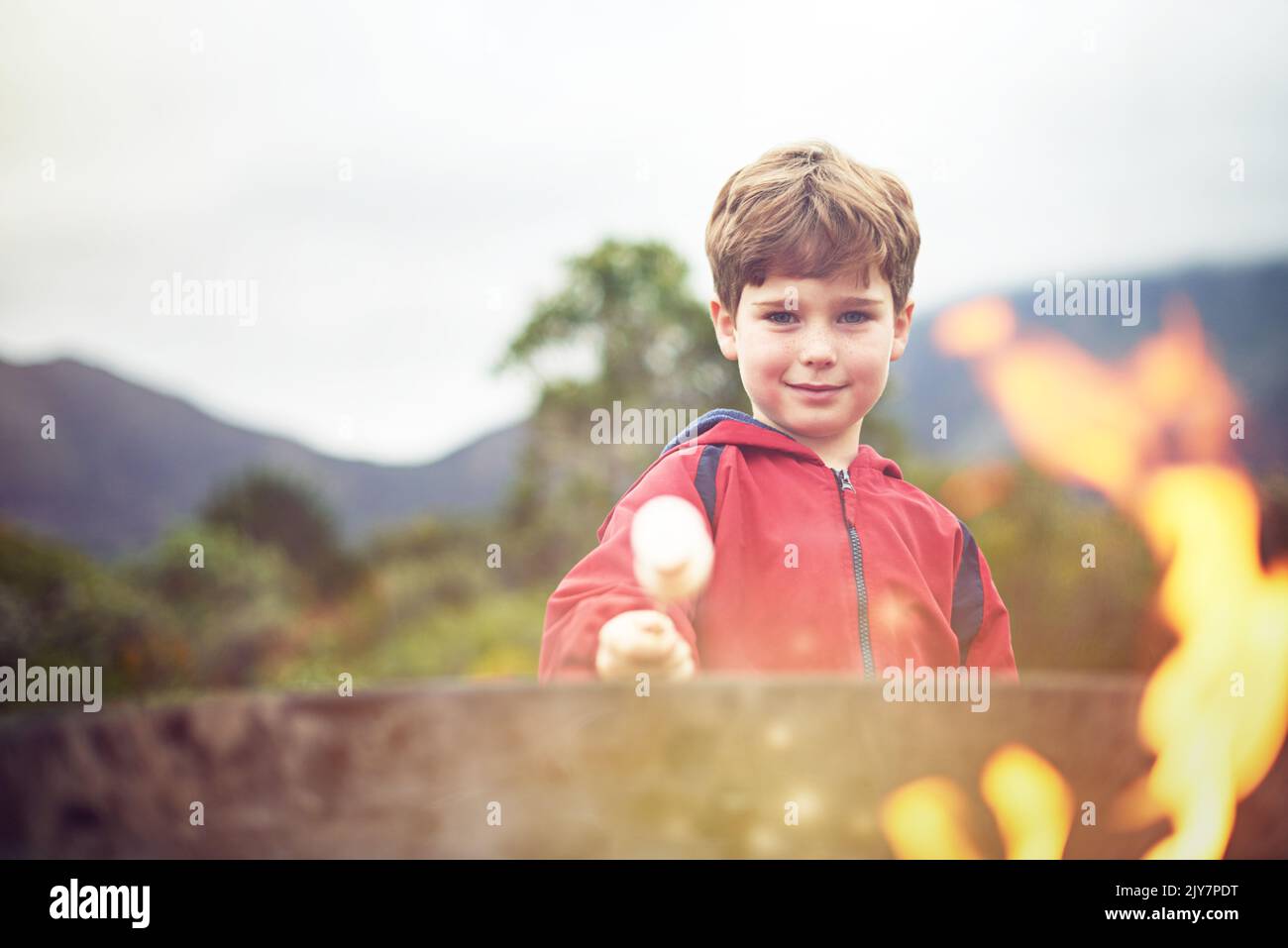 MMM... Marshallows. Porträt eines kleinen Jungen, der eine Marschmanne über einem Feuer röstet. Stockfoto