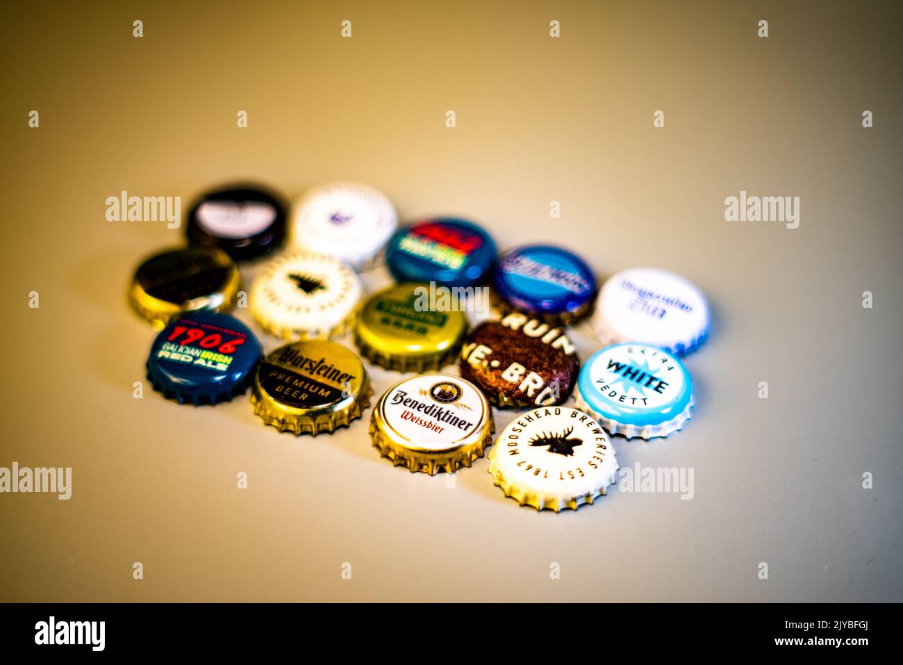Eine Vielzahl internationaler Bierflaschenverschlüsse, die in Reihen auf einem Holztisch angeordnet sind. Stockfoto