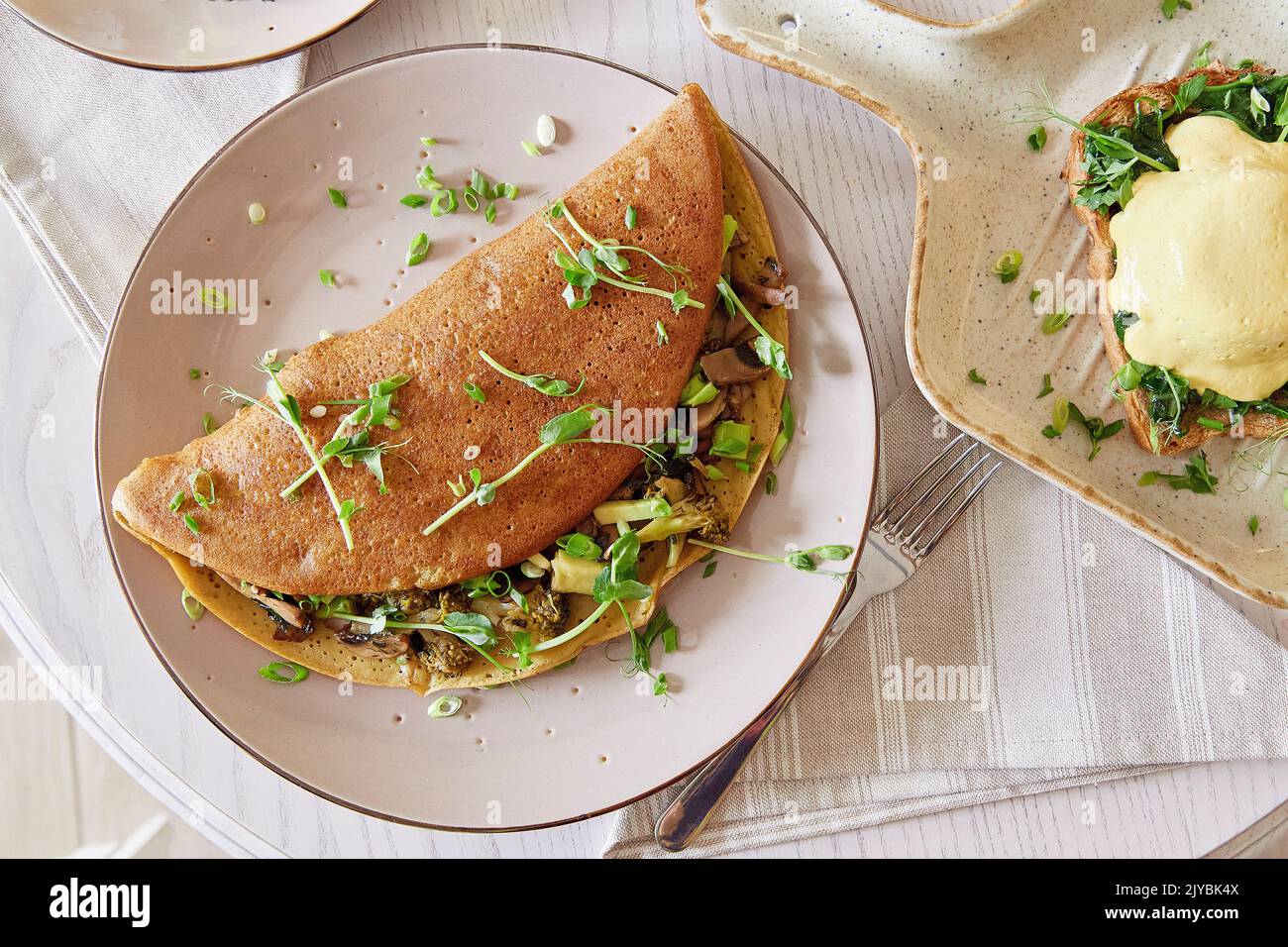 Vegane Pfannkuchen gefüllt mit Pilzen, Erbsensprossen, Avocado. Eier