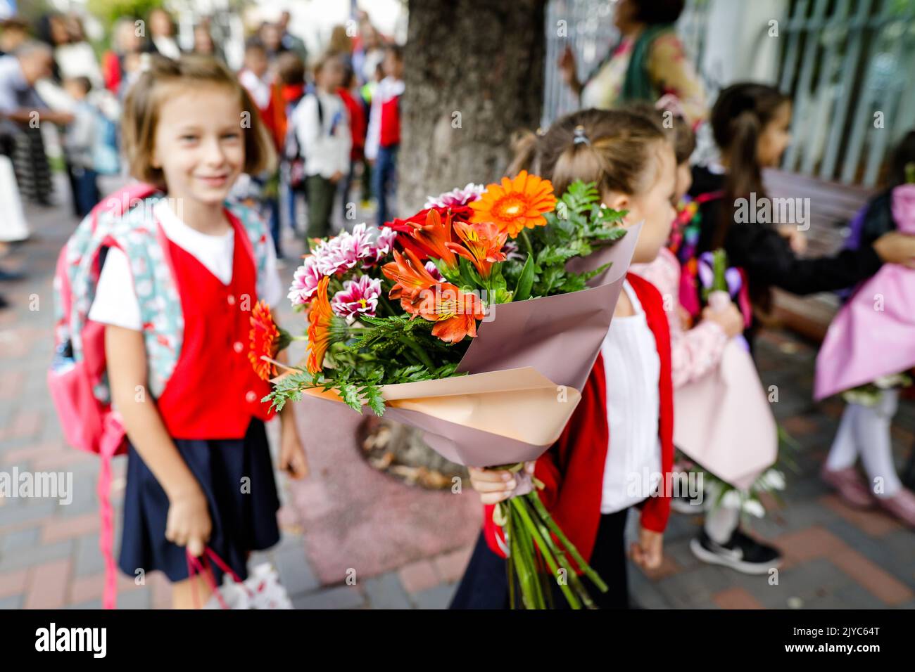 Details zur geringen Schärfentiefe (selektiver Fokus), bei der ein Schulmädchen während des ersten Schultages Blumen für ihren Lehrer hält. Stockfoto