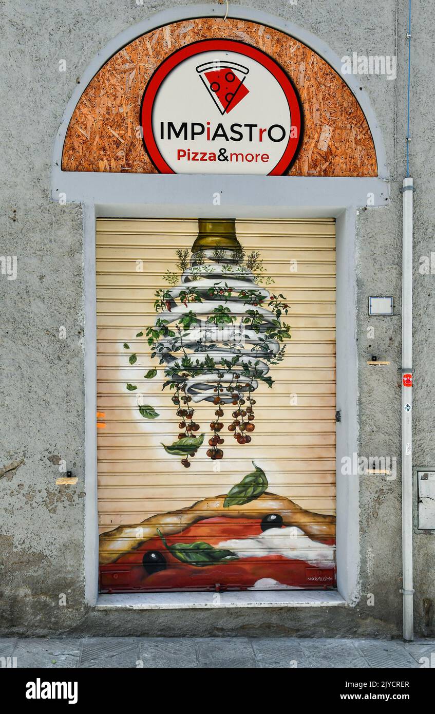 Das abgesenkte Tor einer Pizzeria, die mit einem farbenfrohen Gemälde im historischen Zentrum von Grosseto, Toskana, Italien dekoriert ist Stockfoto