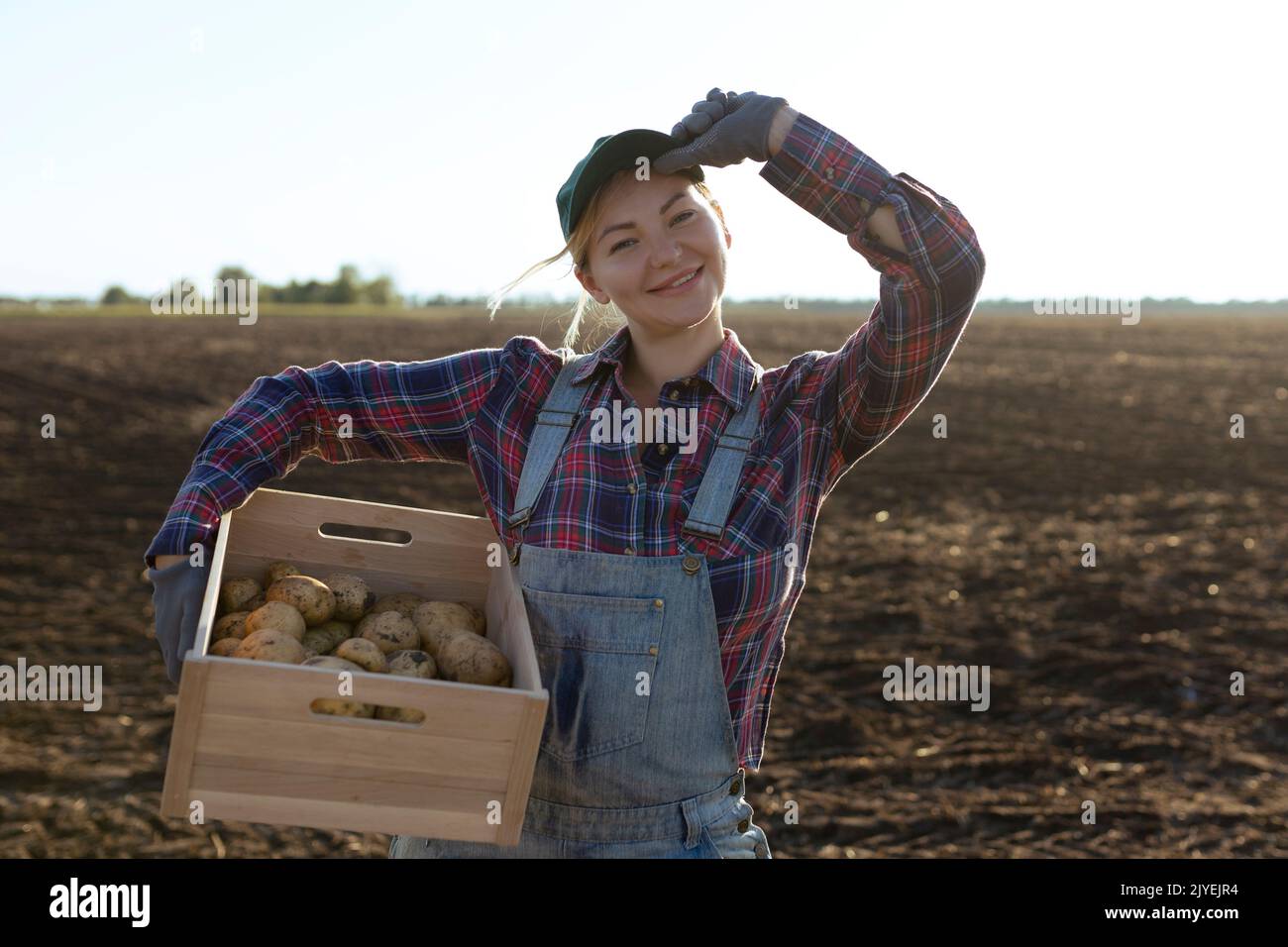 Glücklich lächelnde kaukasische Kartoffelbäuerin oder Gärtnerin. Landwirtschaft - Lebensmittelproduktion, Erntekonzept Stockfoto
