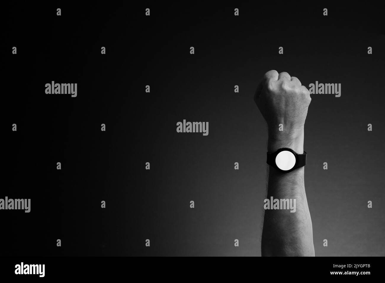 Schwarz-Weiß-Bild der Hand des Mannes mit Smart Watch am Handgelenk, Anzeige weißen leeren Bildschirm, isoliert auf dunklem Hintergrund mit Kopierraum Stockfoto