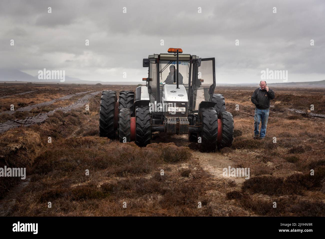 Rasenschnitt mit einer Sausager-Maschine hinter einem Traktor. An ruft mit einem Kunden an. Stockfoto