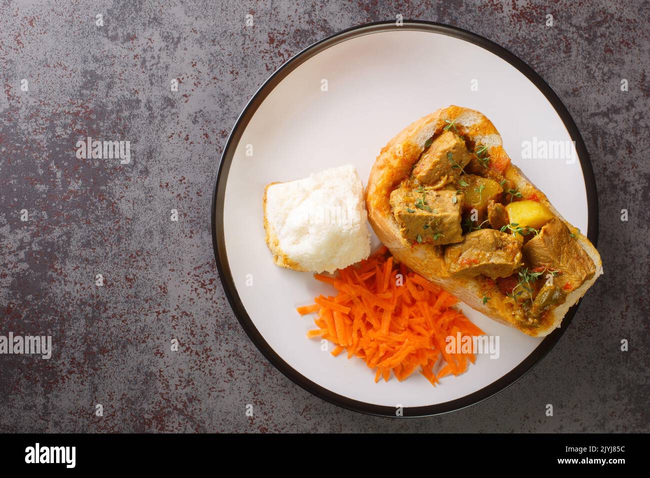 Nahaufnahme von Lammhase Chow die beliebte, indische Fast-Food-Küche, die aus Südafrika stammt, mit Karottensalat auf dem Tisch. Horizontal Stockfoto