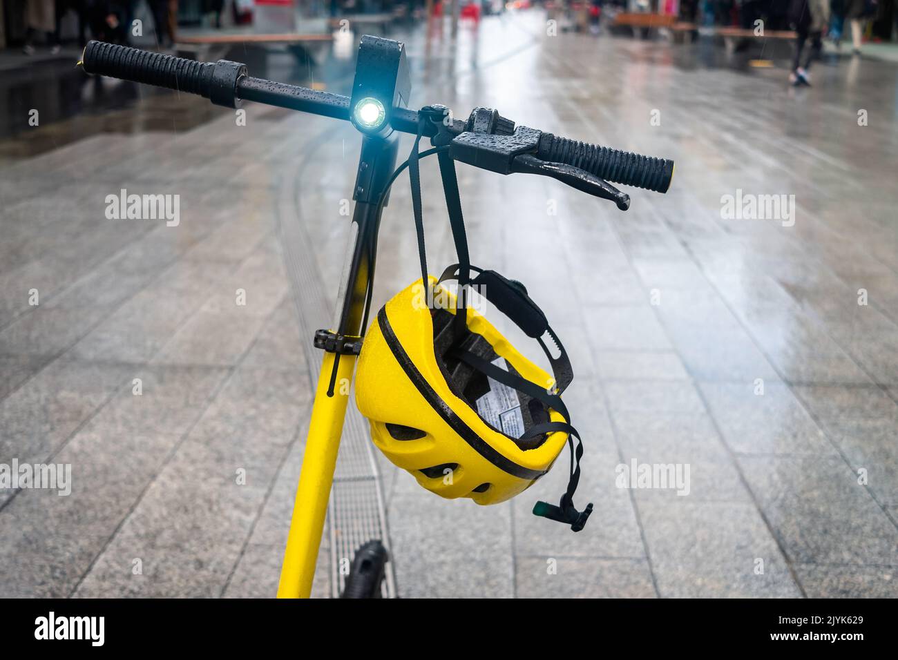 Elektroroller mit Helm und Licht auf geparkt auf einer Straße an einem regnerischen Tag Stockfoto