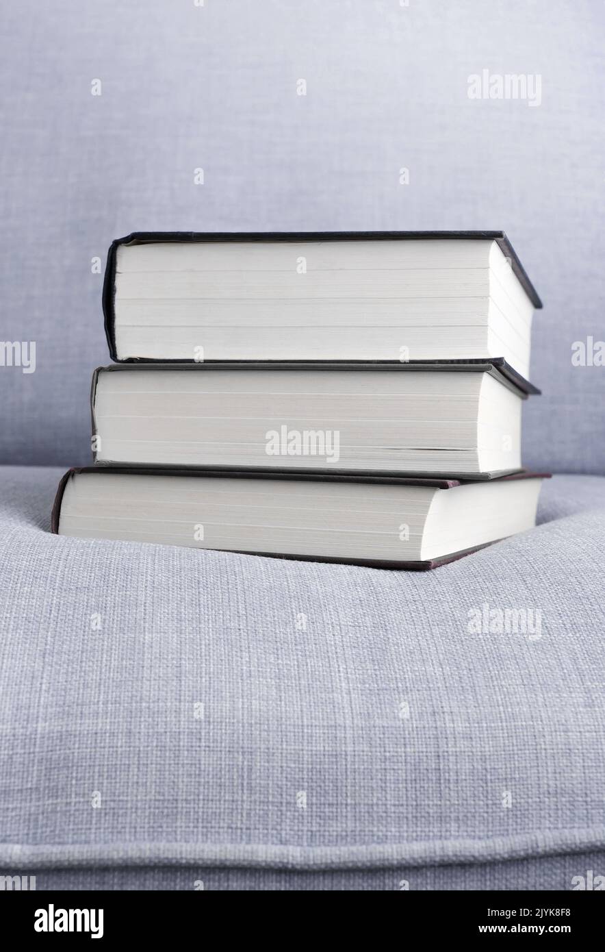 Stapel von drei Hardback-Büchern auf dem Sofa Kopiere Platz oben und unten Stockfoto