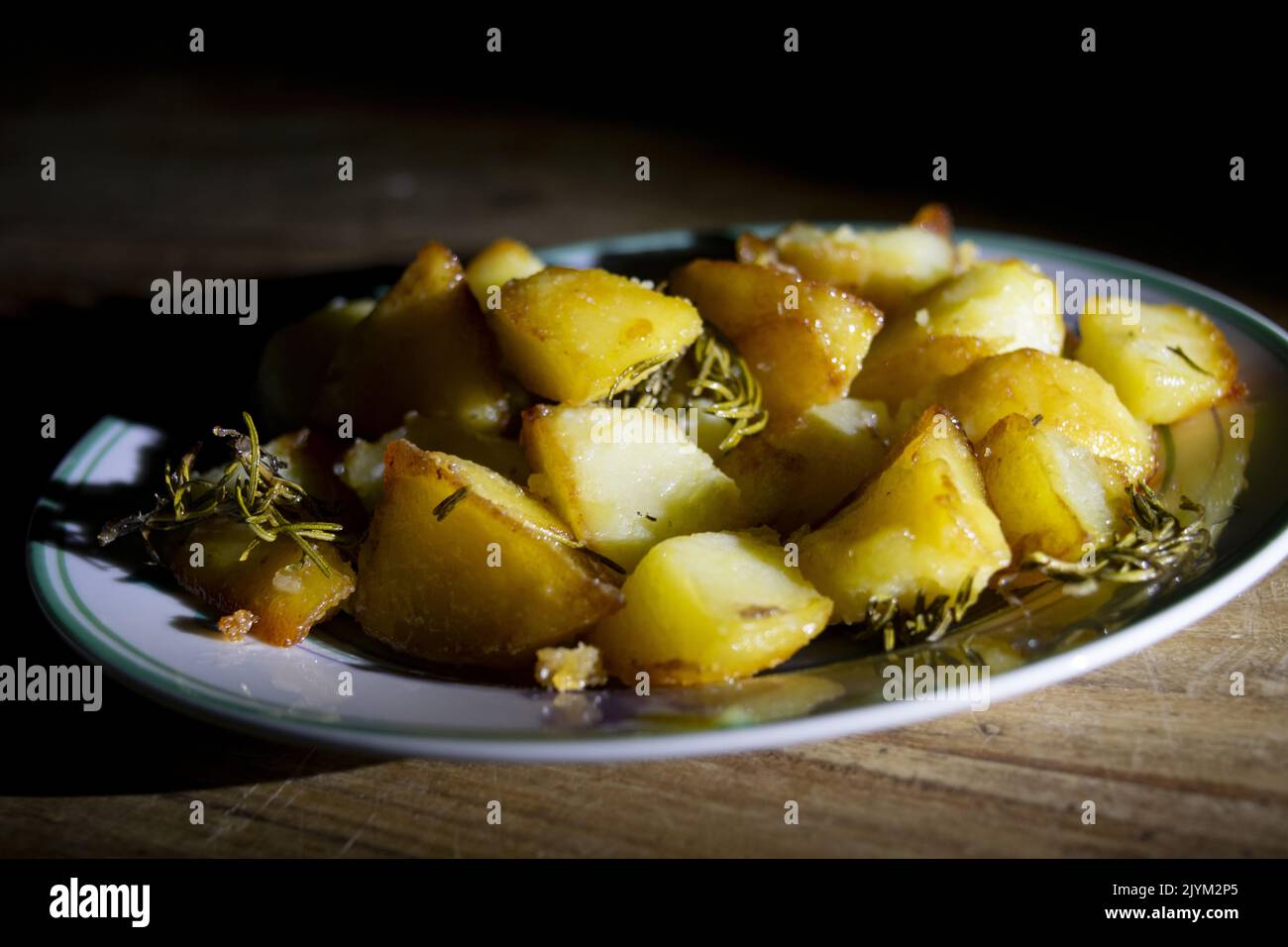 Gericht aus gebackenen Kartoffeln mit Kräutern und Chiaroscuro Licht Stockfoto