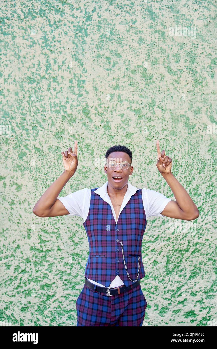 afroamerikanischer Mann mit einer Brille, die zur Seite zeigt, und einem Finger, der auf grünem Hintergrund isoliert ist Stockfoto