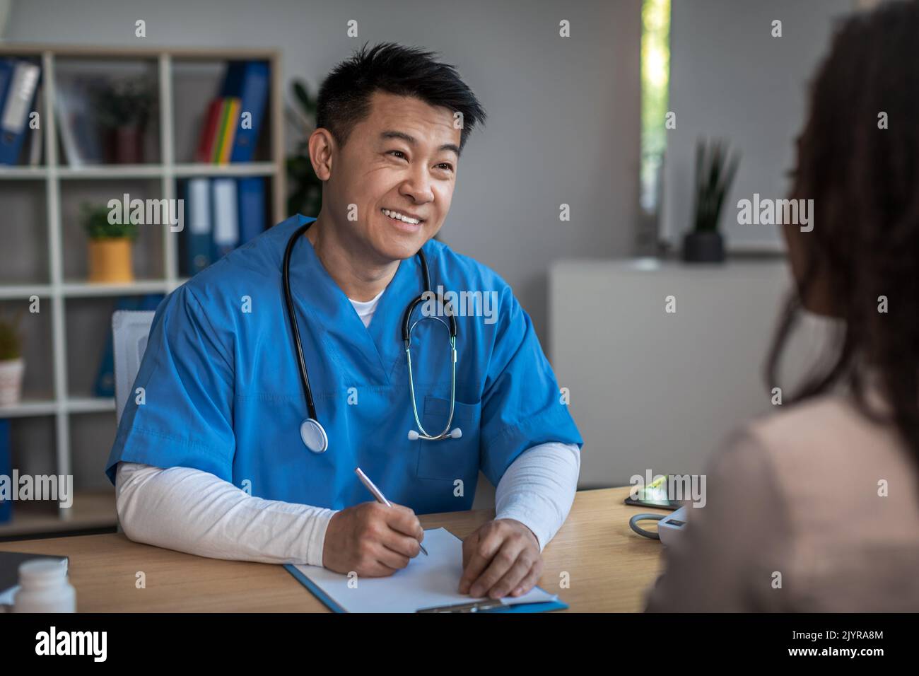 Fröhlich freundlich reifen koreanischen Mann Arzt Beratung junge afroamerikanische Dame Patient in der Klinik Stockfoto