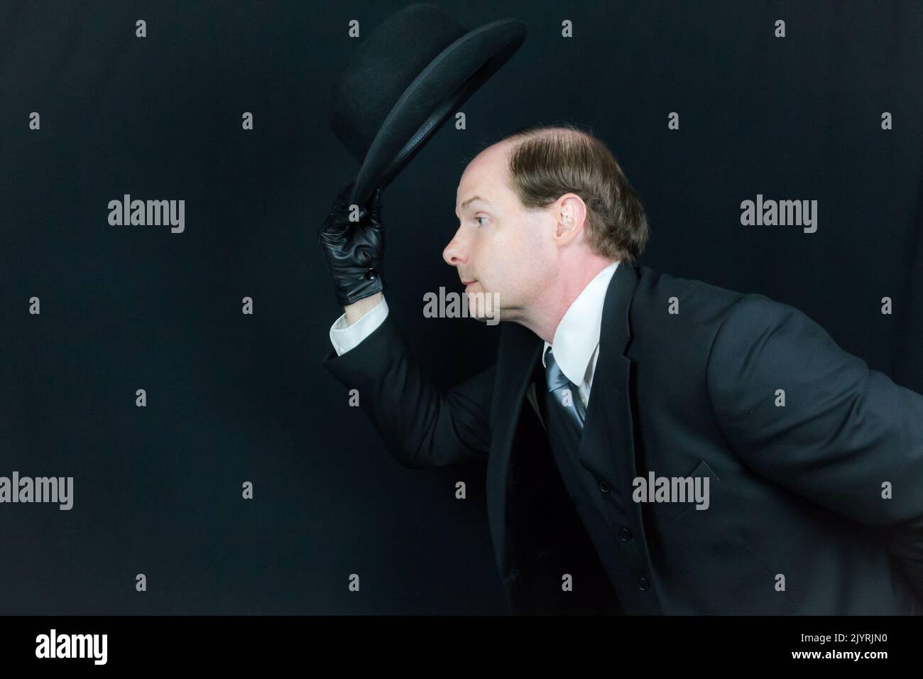Porträt eines britischen Geschäftsmannes in schwarzem Anzug und Lederhandschuhe Bowler Hut kippen und sich in höflicher Begrüßung beugen. Klassischer Englischer Gentleman Stockfoto