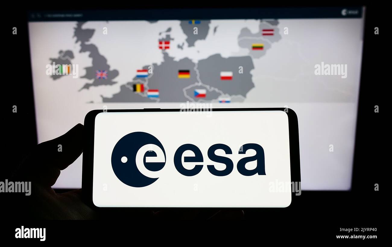 Person, die das Smartphone mit dem Logo der europäischen Organisation European Space Agency (ESA) auf dem Bildschirm vor der Website hält. Konzentrieren Sie sich auf die Telefonanzeige. Stockfoto