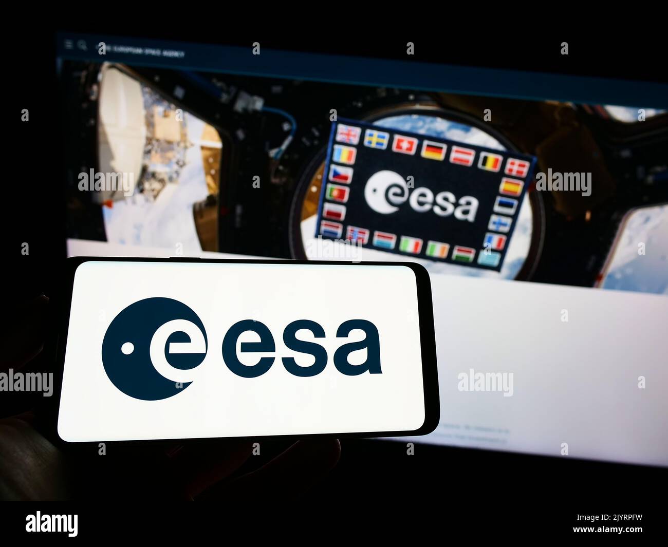 Person mit Mobiltelefon und Logo der europäischen Organisation European Space Agency (ESA) auf dem Bildschirm vor der Webseite. Konzentrieren Sie sich auf die Telefonanzeige. Stockfoto