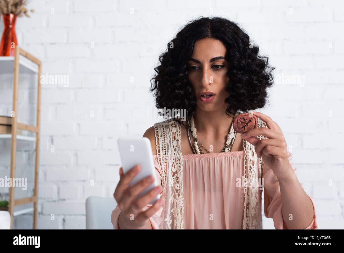 Brunette Wahrsagerin Blick auf Handy und hält Ton Rune Stockfoto