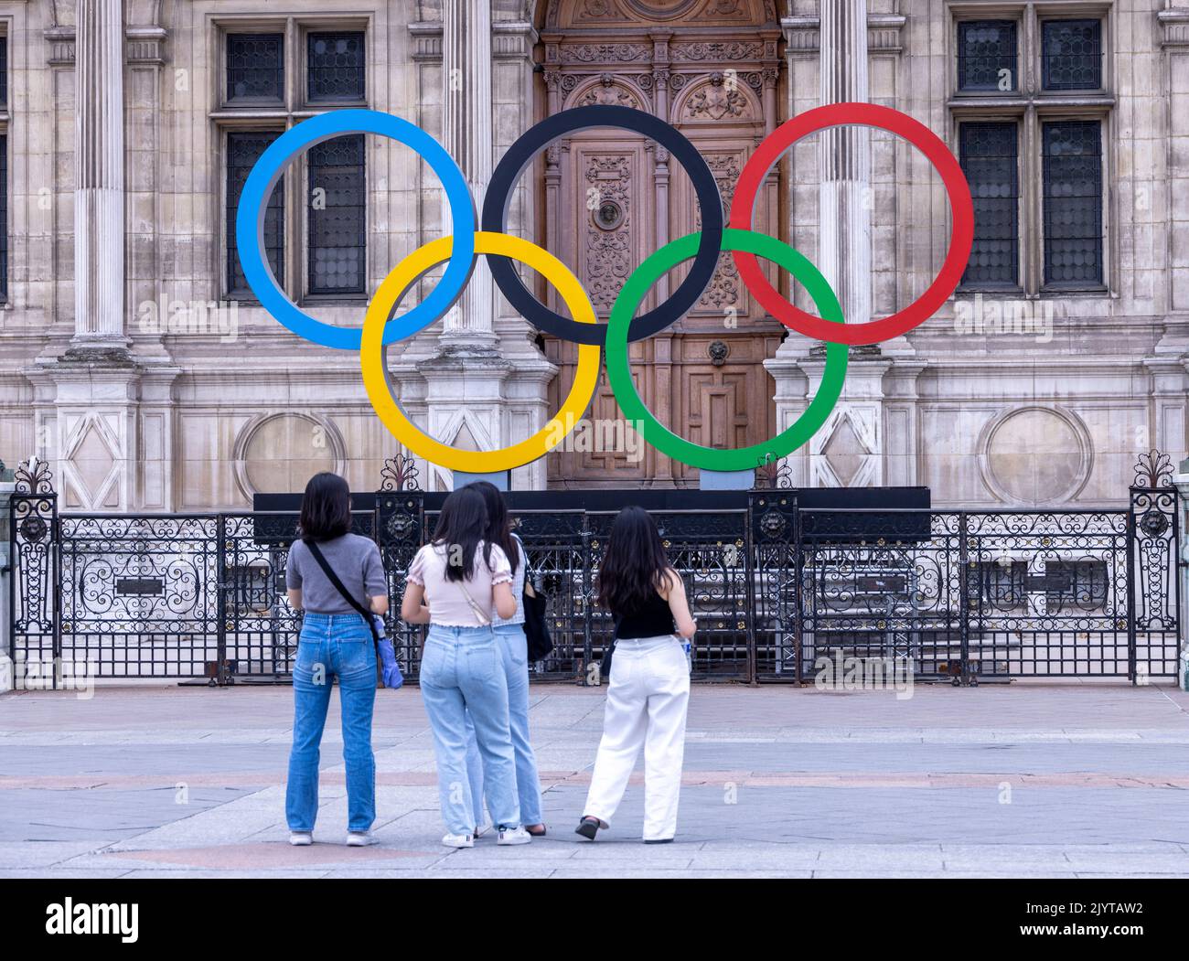 Asiatische Touristen fotografieren vor dem Schild der Olpymic Games am Hôtel de Ville, dem Rathaus von Paris, Frankreich Stockfoto