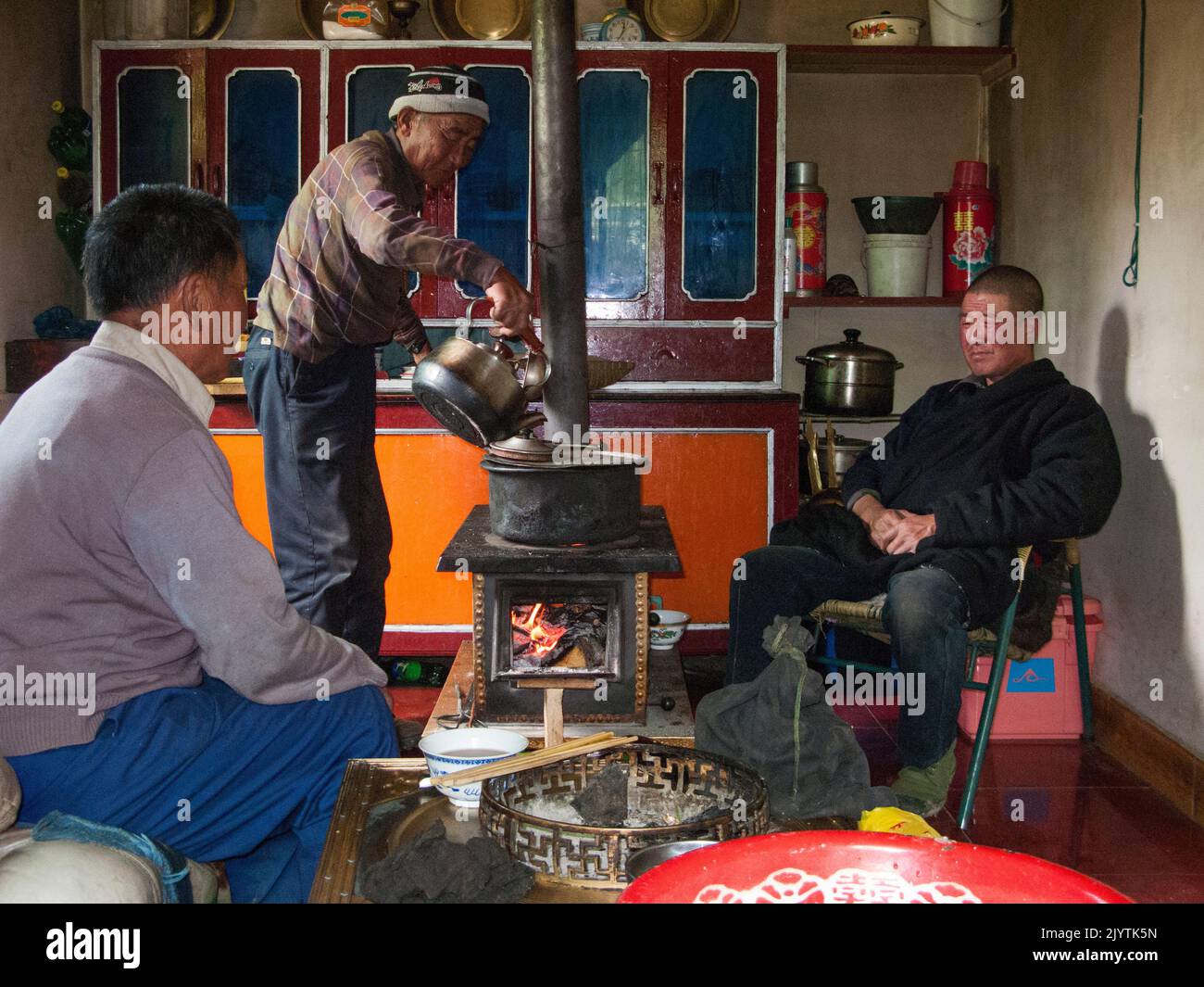 Männer einer tibetischen ethnischen Familie, die in einem kleinen Dorf außerhalb der antiken Stadt Songpan in der nördlichen Provinz Sichuan, China, Speisen zubereiten, kochen und Nudelgerichte essen, die für einen westlichen Touristenbesuch zubereitet werden. VRC. (126) Stockfoto
