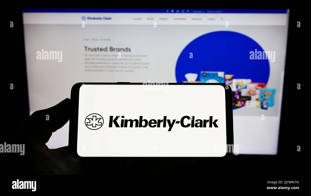Person, die das Smartphone mit dem Logo des Körperpflegeunternehmens Kimberly-Clark Corporation auf dem Bildschirm vor der Website hält. Konzentrieren Sie sich auf die Telefonanzeige. Stockfoto