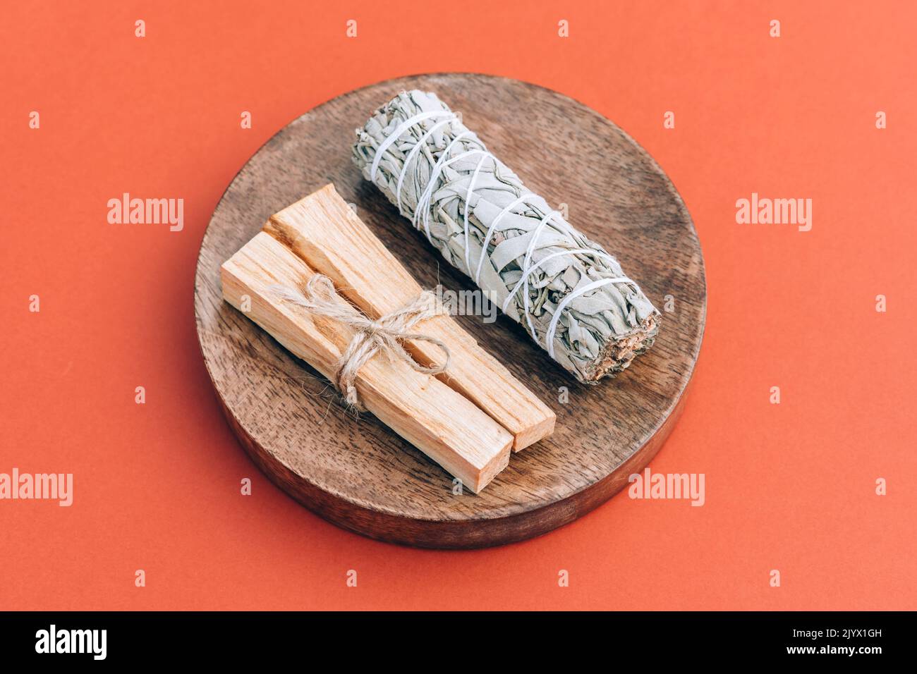 Weihrauchbündel für Meditation und Raumbegasungsritual. Weißer Salbei und palo santo-Stäbe auf Holzpodium auf rotem Hintergrund. Holy Wood Sticks. Sel Stockfoto