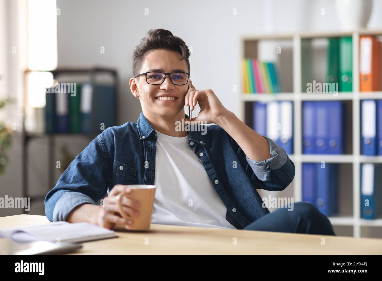 Hübscher Junger Mann, Der Während Der Kaffeepause Im Büro Telefongespräche Führt Stockfoto