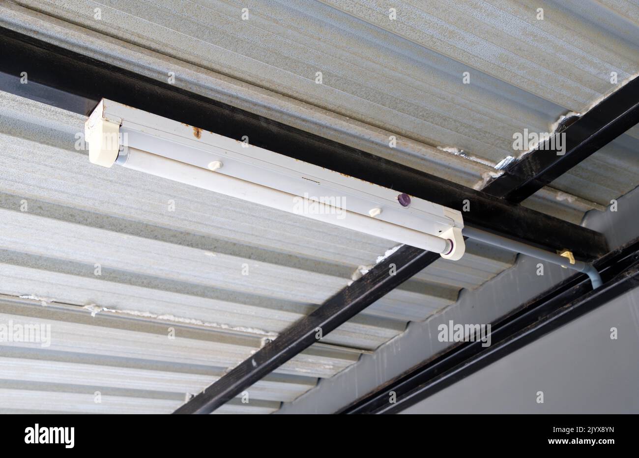 Die Leuchtstofflampe hängt am Metallrahmen des Daches im Stadthaus, Vorderansicht mit dem Kopierraum. Stockfoto