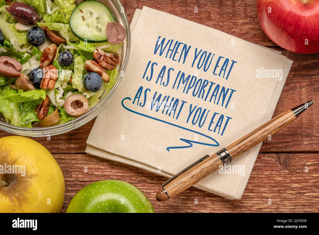 Wenn Sie essen, ist so wichtig wie das, was Sie essen - inspirierende Notiz auf einer Serviette mit einem gesunden Salat und Äpfeln, gesunde Ernährung und Lifestyle-Konzept Stockfoto