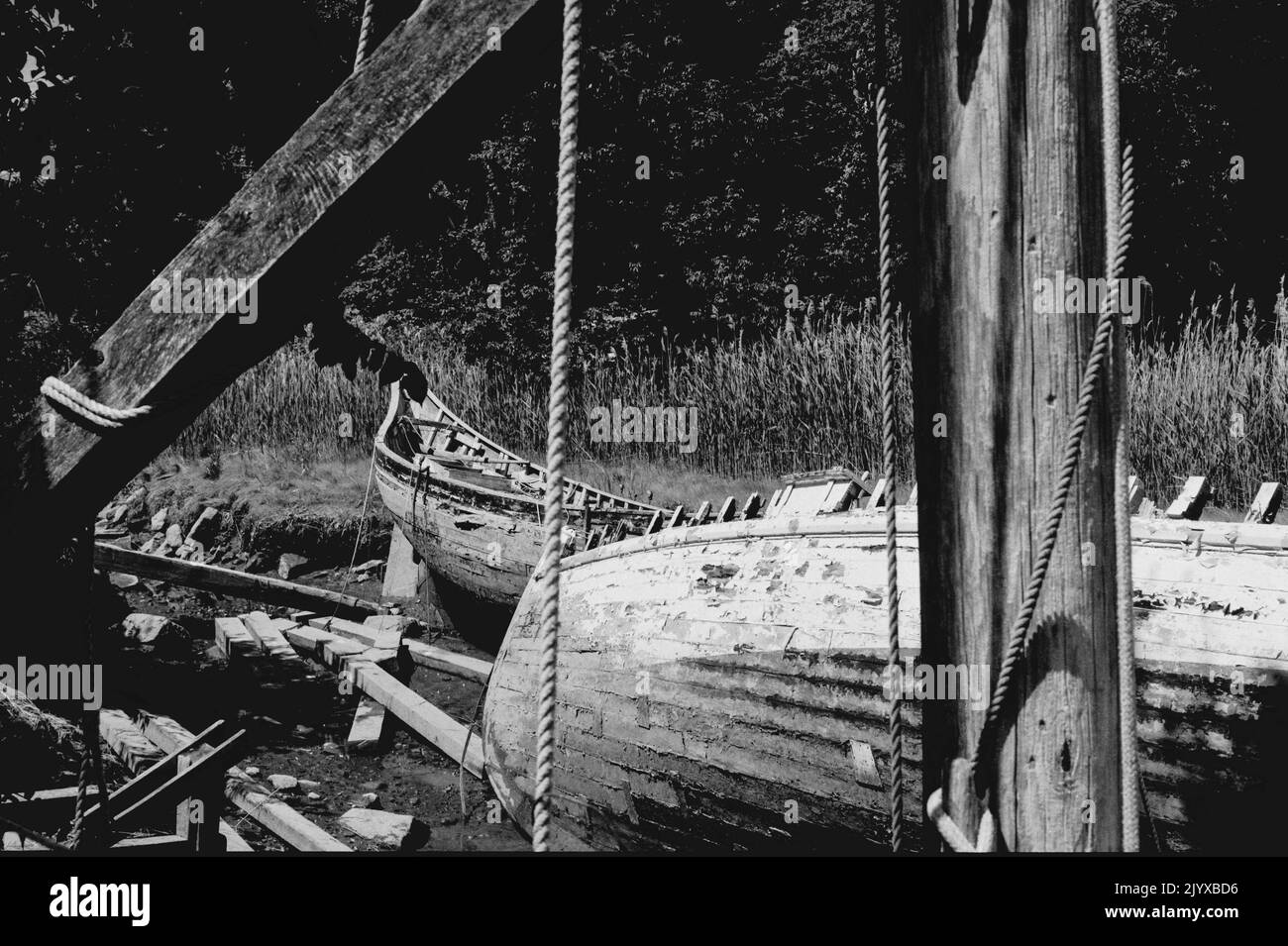 Zwei verfallende und verlassene Holzboote werden bei Ebbe im Essex Shipbuilding Museum - Essex, Massachusetts, enthüllt. Mit Analo aufgenommenes Bild Stockfoto