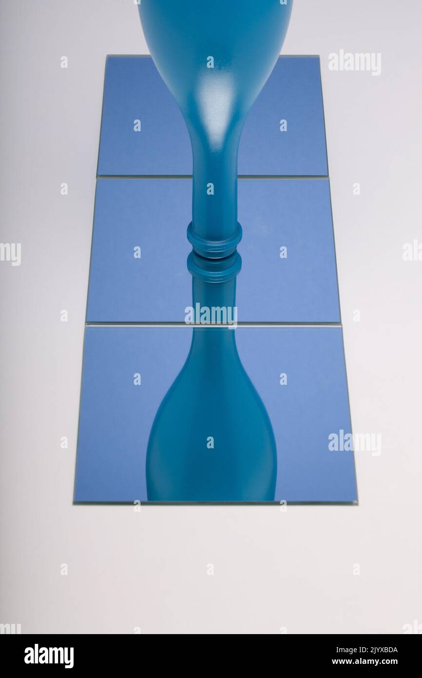 Horizontales Bild des Spiegels mit Reflektion blaue Flasche in blauen Spiegel. Konzept der Weinprodukte. Stockfoto