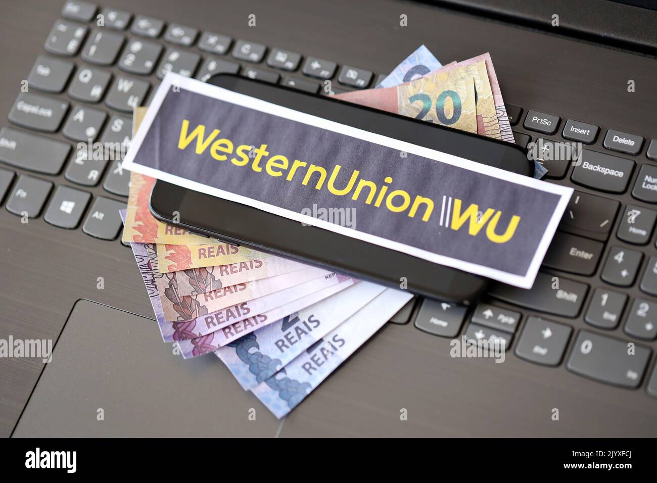 TERNOPIL, UKRAINE - 6. SEPTEMBER 2022 Western Union Papierlogo liegt auf schwarzer Laptop-Tastatur mit brasilianischen reals Rechnungen. WESTERN Union Company IS Stockfoto
