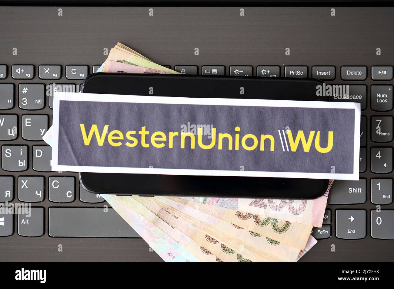 TERNOPIL, UKRAINE - 6. SEPTEMBER 2022 Western Union Papierlogo liegt auf schwarzer Laptop-Tastatur mit ukrainischen Griwnien. WESTERN Union Company ist Ame Stockfoto