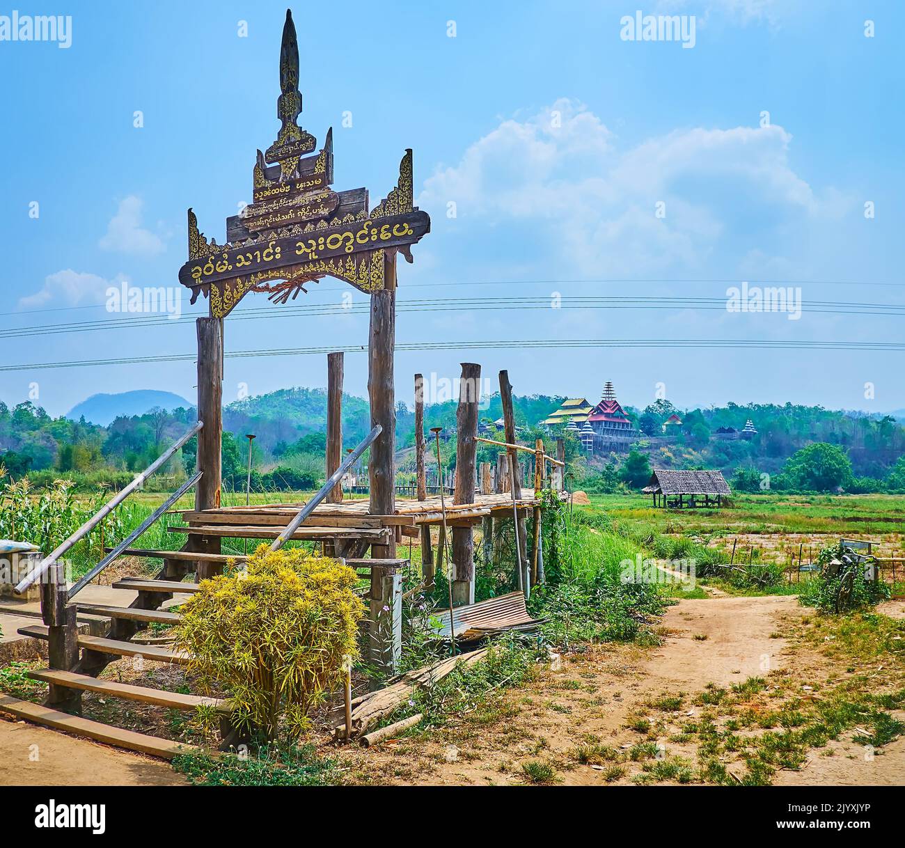 Geschnitztes Vintage-Holztor der Su Tong Pae Bambusbrücke, das entlang der landwirtschaftlichen Flächen im Vorort Mae Hong Son, Thailand, verläuft Stockfoto