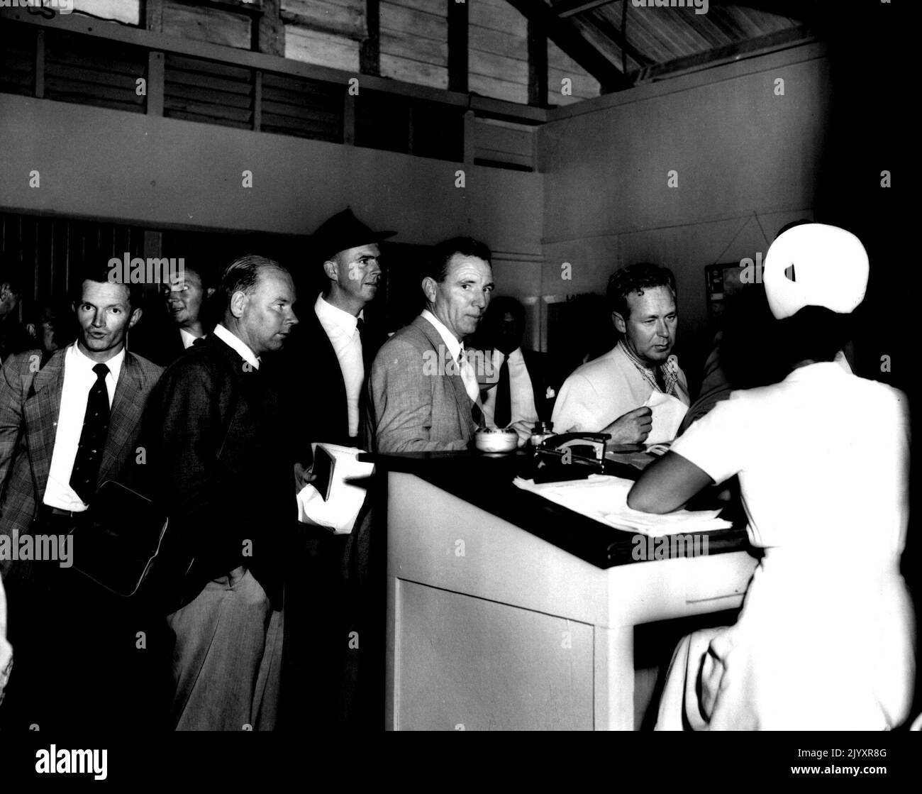 Spieler überprüfen ihre Papiere bei einer Krankenschwester für Immigration. 22. Juli 1955. Stockfoto