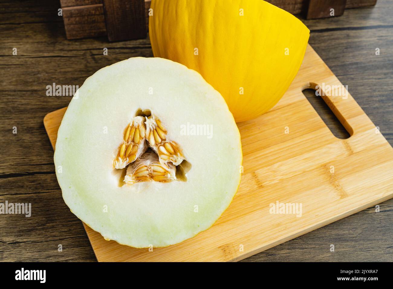 Leckere gelbe Melone in zwei Hälften geschnitten, auf Holzbrett. Stockfoto