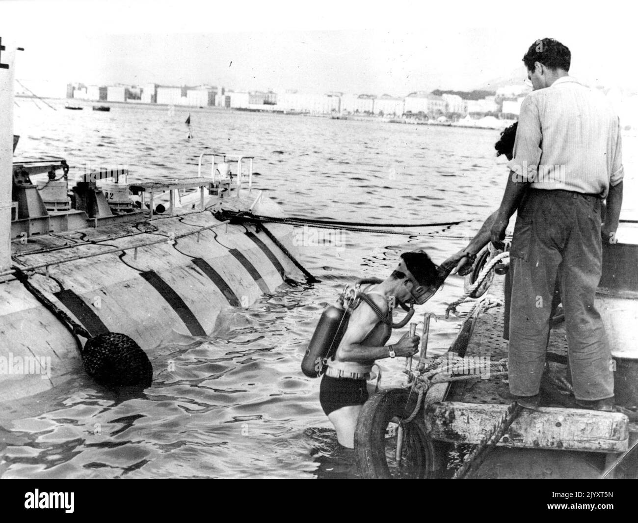 Piccard Junior inspiziert unter Wasser Performance -- Jacques Piccard, Sohn von Prof. Auguste, steigt mit seiner Maske und seinem Atemgerät an Bord eines Hilfskraftfahrzeugs, nachdem er die Unterwasserperformance der Bathysphäre untersucht hat. Es heilte eine seiner Inspektionen, dass er ein schweres Benzin-Leck entdeckte, das den 69-jährigen Schweizer Wissenschaftler dazu veranlasste, seinen geplanten Tauchgang auf 4.000 Meter zu verschieben. In der Bathysphäre hat das Benzin nur eine hydrostatische Funktion, während die beiden kleinen Propeller, mit denen das "Sphip" ausgestattet ist, mit elektrischen Batterien angetrieben werden. 27. September 1953. (Foto Stockfoto