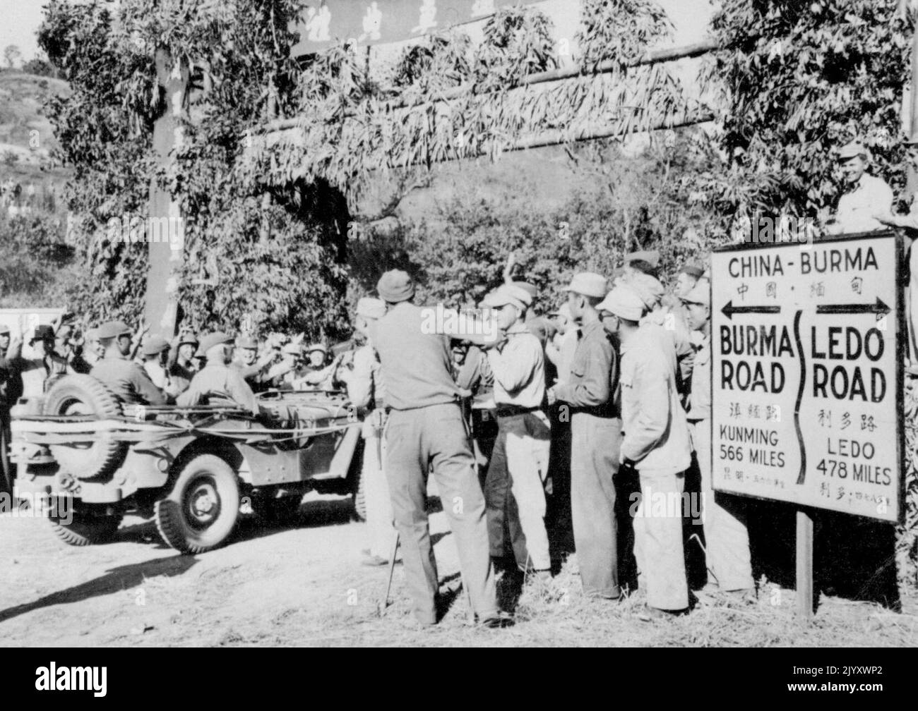 Burma Und Ledo Roads Schlossen Sich An -- Brig. General Lewis B. Pick, Kommandant und Chief Engineer des Ledo Road Bauprojekts fährt in seinem Jeep durch einen Torbogen, der die Kreuzung der Burma- und Ledo-Straßen markiert. Amerikanische und chinesische Truppen stehen am Straßenrand und jubeln über die Gelegenheit. Die Straße von Ledo hat zu Ehren des Generals Pick den inoffiziellen Titel „Pick's Pike“ verliehen. 17. Februar 1945. (Foto von Associated Press Photo). Stockfoto